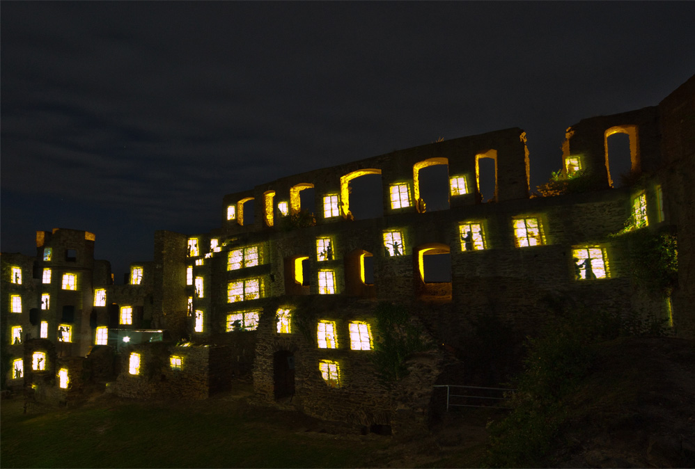 Burg Rheinfels erscheint mit hellen Fenstern und Menschen in den Fenstern